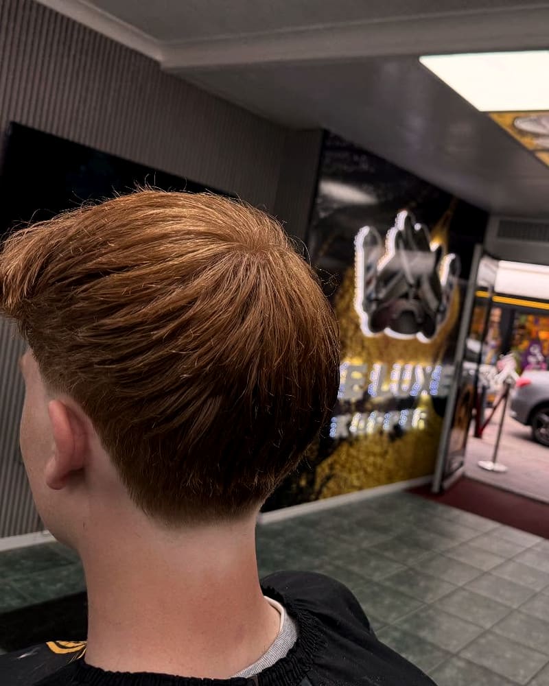 Low fade met een koperbruine crop, van achteren